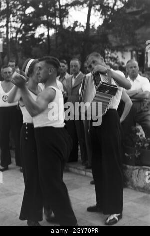 Musik und Tanz vor Waldhütten des KdF Sportheim Belzig in der Mark Brandenburg, Deutschland 1930er Jahre. La gente di cantare e ballare nella parte anteriore dei rifugi forestali presso il club sportivo a Belzig nel Brandeburgo, Germania 1930s. Foto Stock