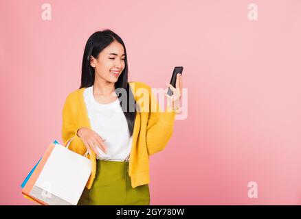 Ritratto Asiatico felice giovane donna teen shopper sorridente in piedi eccitato tenendo online borse shopping online colorato multicolore e smartphon Foto Stock