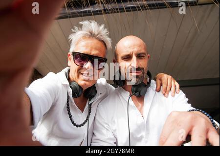 Disco jockey guardare la macchina fotografica e fare selfie mentre si suona la musica per i turisti al club party all'aperto sulla spiaggia - Musica e divertimento concetto - Foto Stock