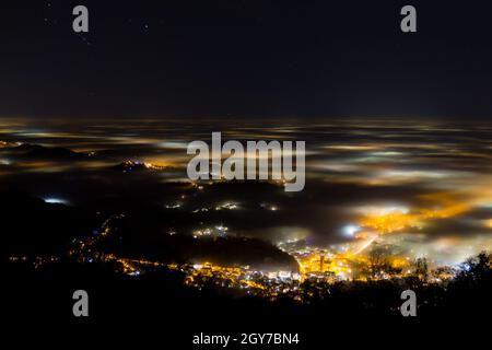 Plain illumina parzialmente coperta dalla nebbia, luci soffuse. Monte Grappa, paesaggio italiano Foto Stock