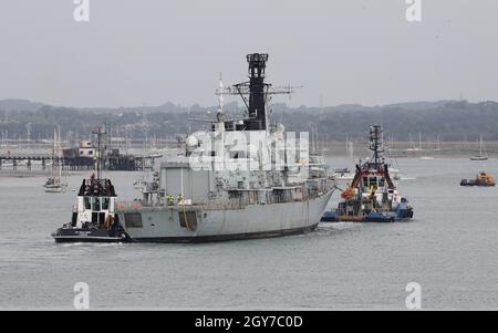 Tugs traina l'ex Royal Navy tipo 23 fregata HMS MONMOUTH nella base navale Foto Stock