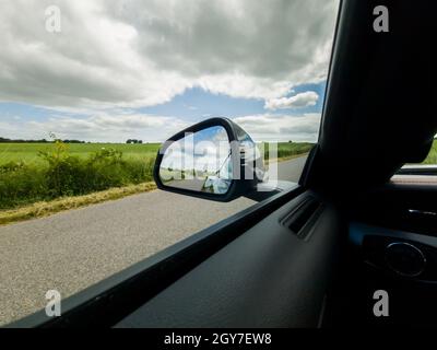 Vista sullo specchietto laterale di una vettura sportiva nera durante la guida Foto Stock