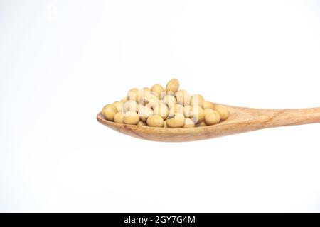 Grano di soia nel cucchiaio di legno isolato su uno sfondo bianco. Foto Stock