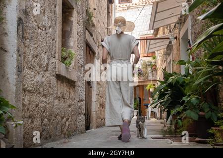 Vista posteriore della bella giovane ragazza bionda che indossa paglia sun hat visite turistiche e godere di una vacanza estiva in un vecchio città costiera tradizionale a Foto Stock