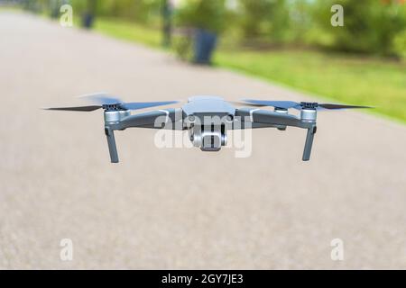 Un quadricottero con una telecamera non vola in alto nell'aria sullo sfondo di un parco pubblico. Foto Stock
