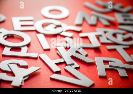 Le lettere piene miste impilano la foto in primo piano. Concetto di istruzione su sfondo rosso. Foto Stock