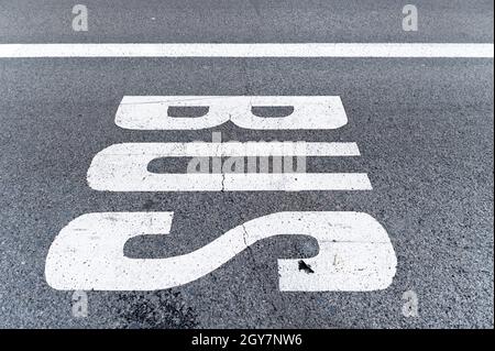 Segnale di autobus dipinto sul marciapiede di una corsia di strada, si può vedere la texture dell'asfalto con una linea spaccata. Segnale e concetto urbano Foto Stock