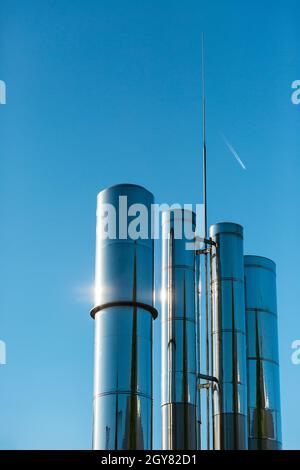 Camini di fabbrica lucidi contro un cielo blu chiaro Foto Stock