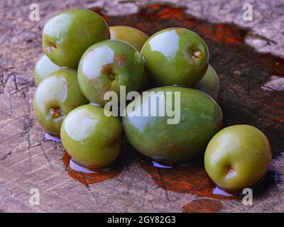 Olive verdi su olio di tavola di legno Foto Stock