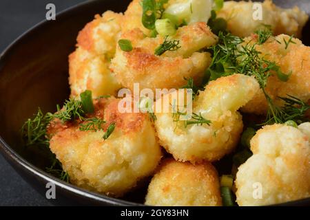 Fiori di cavolfiore fritti in pastella su un piatto nero. Cavolfiore fritto rivestito Foto Stock