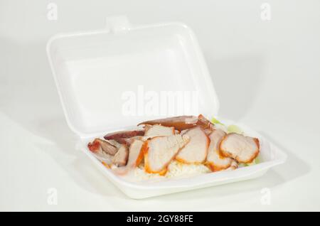 Riso rosso di maiale alla griglia in una scatola di schiuma su sfondo bianco. Fast food e Street food in Thailandia. Foto Stock
