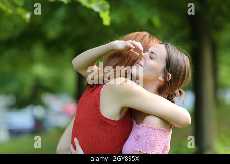 Donna abbracciando la sua amica che tiene il naso per evitare cattivo odore in un parco Foto Stock