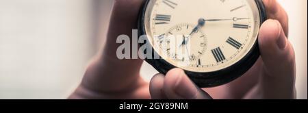 Il tempo passa vicino: L'uomo sta tenendo un orologio d'annata nella sua mano, contesto di affari, spazio di copia Foto Stock