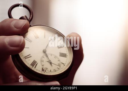 Il tempo passa vicino: L'uomo sta tenendo un orologio d'annata nella sua mano, contesto di affari, spazio di copia Foto Stock