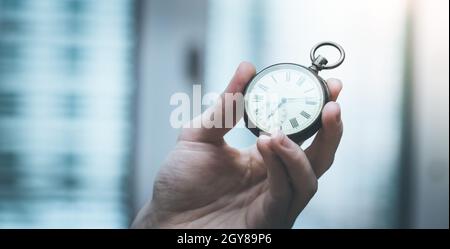 Il tempo passa vicino: L'uomo sta tenendo un orologio d'annata nella sua mano, contesto di affari, spazio di copia Foto Stock