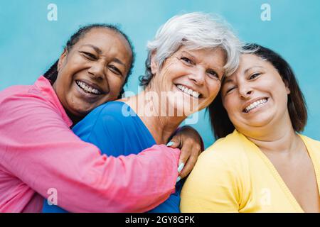 Felice persone anziane diverse abbracciarsi all'aperto - concetto di comunità di amici anziani - Focus sul volto donna centrale Foto Stock