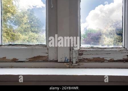 Vecchie finestre di legno con legno marcio e incrinato peeling vernice, casa ha bisogno di ristrutturazione e nuovi telai closeup Foto Stock