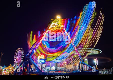 Giostre in fiera e giostre di carnevale di notte con colori e movimento Foto Stock