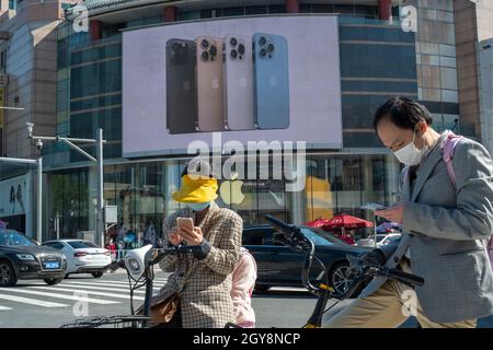 La gente cammina davanti a un negozio Apple a Wangfujing con la serie di pubblicità iPhone 13 su un grande schermo a Pechino, Cina. 07 ottobre 2021 Foto Stock