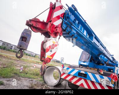 La gru per cantieri sta sollevando un cartello a LED vuoto su sfondo blu cielo per la nuova pubblicità Foto Stock