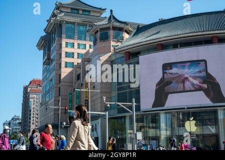 La gente cammina davanti a un negozio di mele a Wangfujing con iPad mini pubblicità su un grande schermo a Pechino, Cina. 07 ottobre 2021 Foto Stock