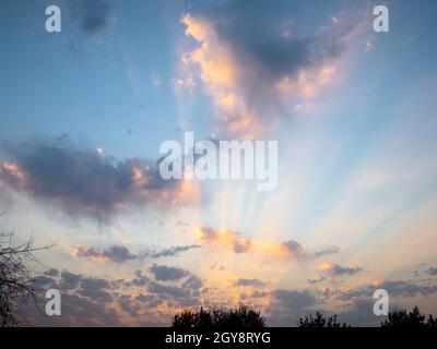 gli ultimi raggi di sole illuminano il cielo blu del tramonto e le nuvole in una serata autunnale Foto Stock