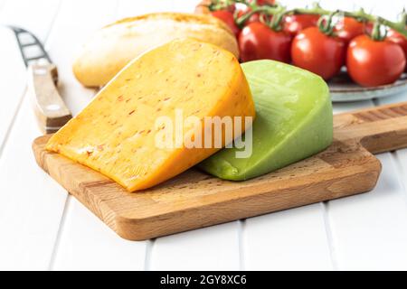 Blocco di formaggi stagionati con sapore di peperoncino e wasabi su tagliere di legno. Foto Stock