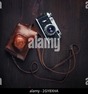 Fotocamera e custodia vintage su sfondo in legno. Vista dall'alto. Disposizione piatta. Foto Stock