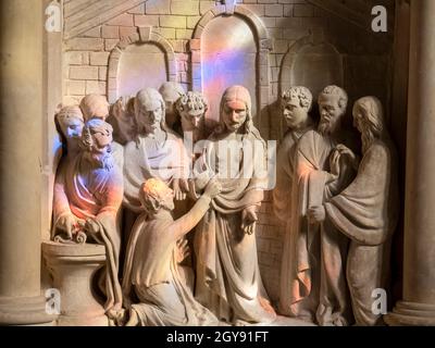 Luce da una vetrata che cade su una scultura in una chiesa di Brome, Suffolk, Regno Unito. Foto Stock