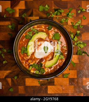 Vista dall'alto di una zuppa cremosa di pollo di enchilada con crema acida di avocado e coriandolo su un tagliere Foto Stock