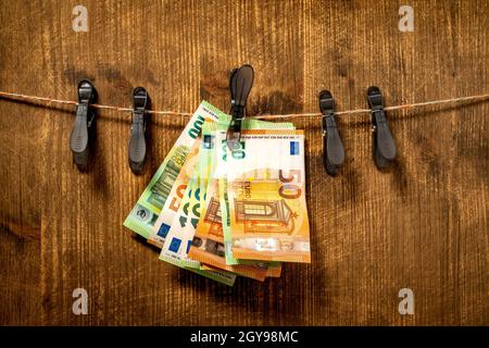 Concetto di riciclaggio di denaro con mazzo di euro sui vestiti linea Foto Stock