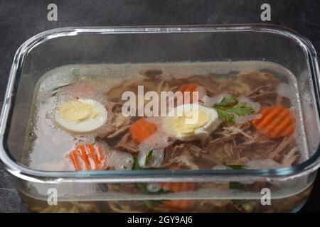 Carne di pollo fatta in casa, aspica, gelatinosa con erbe e carote. Piatto tradizionale russo 'kologets'. Servito con pane e senape o, e rafano Foto Stock