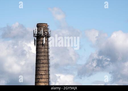 Camino industriale alto con più antenne su sfondo cielo nuvoloso. Foto Stock