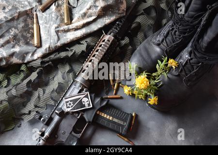 Giorno della memoria israeliana Yom Ha'zikaron. Set militare dell'esercito , stivali da soldato in pelle nera, armi, munizioni e fiori gialli . Concetto di guerra e pace Foto Stock