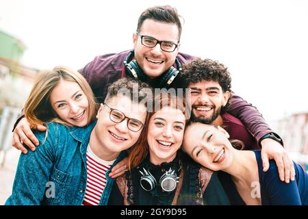 Multiculturale ragazzi e ragazze che prendono selfie all'aperto con la retroilluminazione del giorno - felice idea di stile di vita miliare su giovani uomini e donne che si divertono insieme Foto Stock