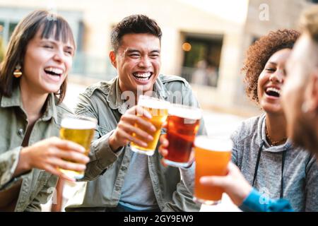Gruppo di amici multietnici felici che bevono e tostano birra al ristorante del bar birreria - concetto di bevanda con uomini e donne che si divertono insieme Foto Stock