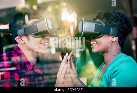 Coppia multirazziale in amore andando oltre la diversità razziale attraverso virtuale Occhiali Reality - giovani che si divertono con la nuova tecnologia Foto Stock