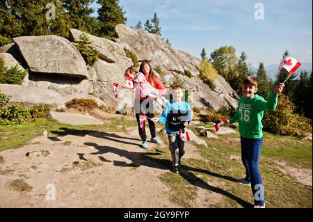 Buon giorno del Canada. Famiglia di madre con tre bambini tenere grande festa canadese bandiera in montagna. Foto Stock
