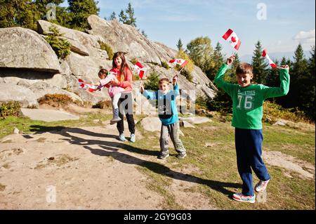 Buon giorno del Canada. Famiglia di madre con tre bambini tenere grande festa canadese bandiera in montagna. Foto Stock
