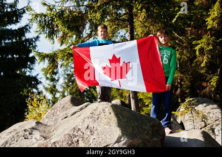 Buon giorno del Canada. Due fratelli con grande bandiera canadese festeggiamenti in montagna. Foto Stock