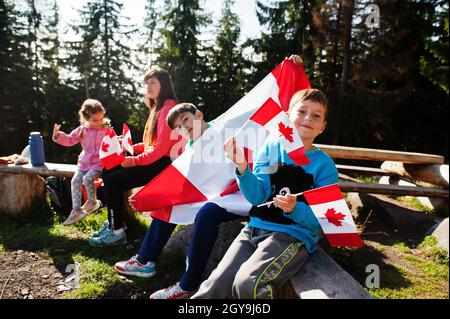 Buon giorno del Canada. Famiglia di madre con tre bambini tenere grande festa canadese bandiera in montagna. Foto Stock