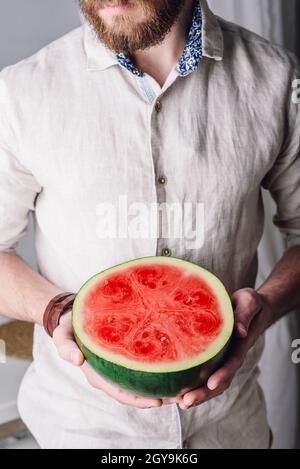 Uomo portato in camicia di lino con metà di cocomero maturo in mano Foto Stock