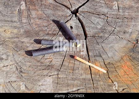 Tre petardi e corrispondenza giacente su un ceppo di albero. Foto Stock
