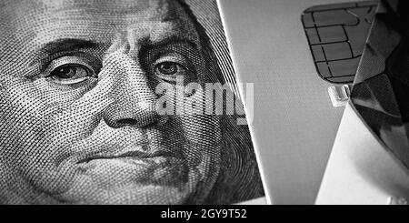 Il volto di Benjamin Franklin su un conto di cento dollari accanto ad una carta di credito. Primo piano. Un conto americano di cento dollari con gli occhi di Benjamin Franklin. Foto Stock