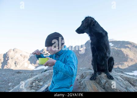 Un ragazzo che mangia la prima colazione mentre si accampava a Glacier Peak Wilderness Foto Stock