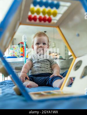 Adorabile bambino seduto sul pavimento analizzando il giocattolo. Foto Stock