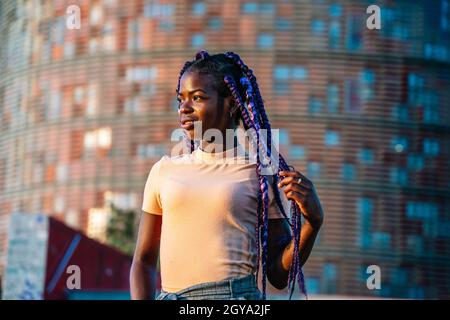 Giovane donna nera con trecce viola sorridenti Foto Stock