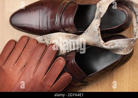 Scarpe classiche marrone uomo, cravatta, guanti, su pavimento in legno, può essere usato come sfondo Foto Stock