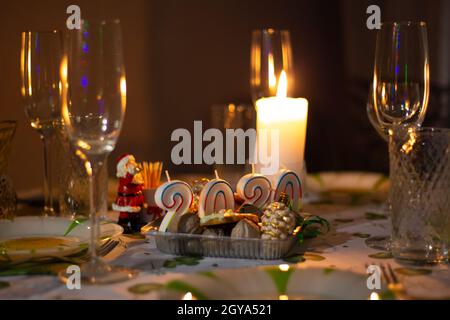 Tavolo di Natale con utensili e bicchieri, un tavolo con candele a legna, in una stanza buia Foto Stock