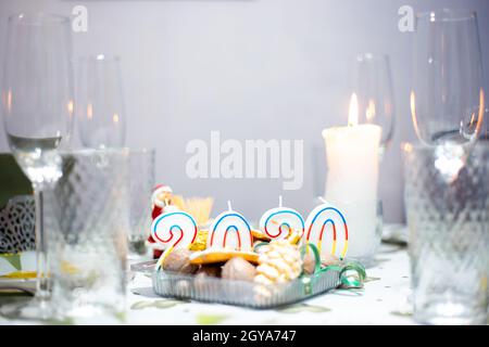 Tavolo di Natale con utensili e bicchieri, un tavolo con candele a legna, in una stanza buia Foto Stock